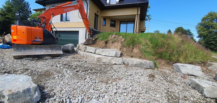 uploads/artykul-kamien-na-skarpie-w-ogrodzie/ukladanie-kamieni-na-skarpie-koparka.jpg